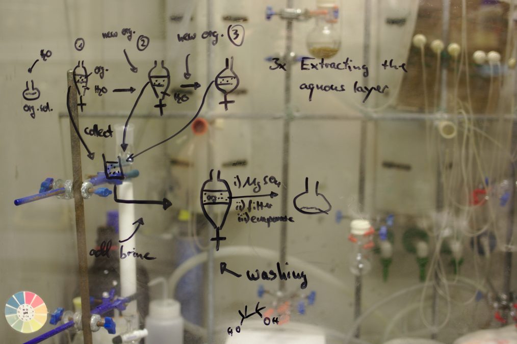 Equations written with a black dry erase marker on a glass in a lab setting