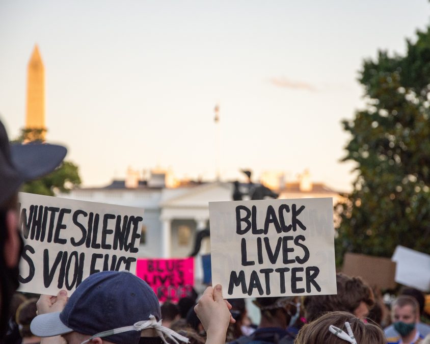 A Black Lives Matter protest outside of the White House. Proteters hold signs that say "WHITE SILENCE IS VIOLENCE" and "BLACK LIVES MATTER" A blog post "Protests and Pandemics: Support and Resources" by Deborah Beckwin