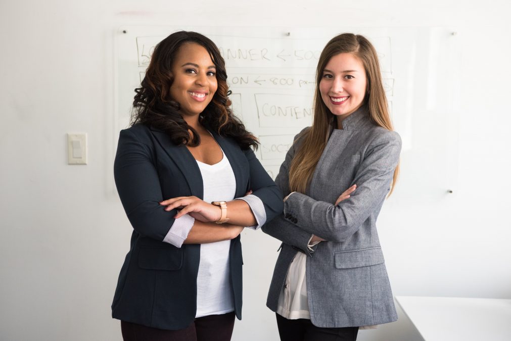Two women in suits standing in front of a white board | Small Business Life — Can't Do It Alone, a blog post by Deborah Beckwin
